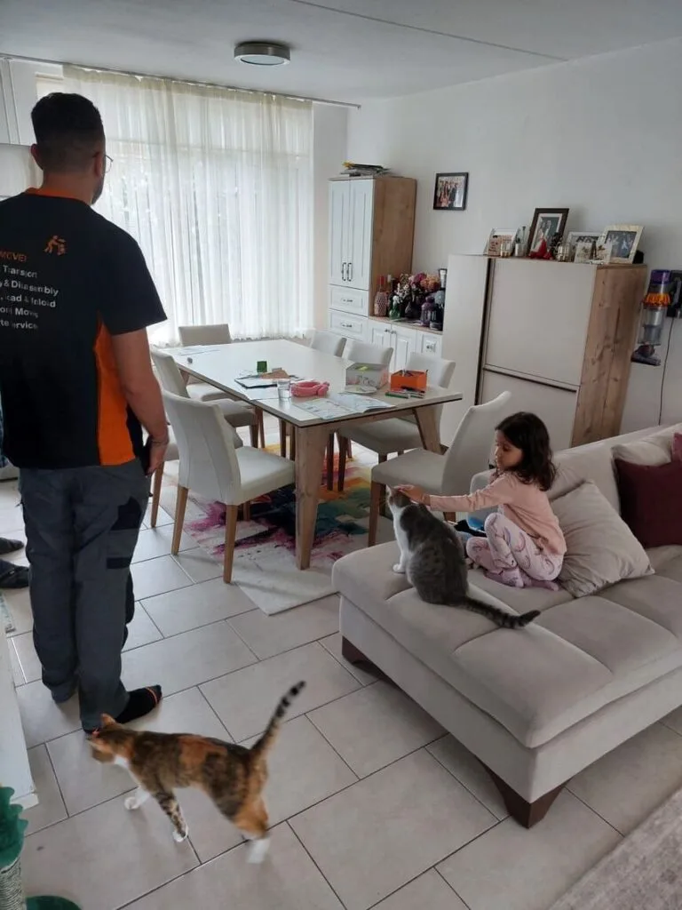 Verhuizer in Eindhoven omringd door twee katten en een kind, gebruikmakend van verhuisliftdiensten in Eindhoven